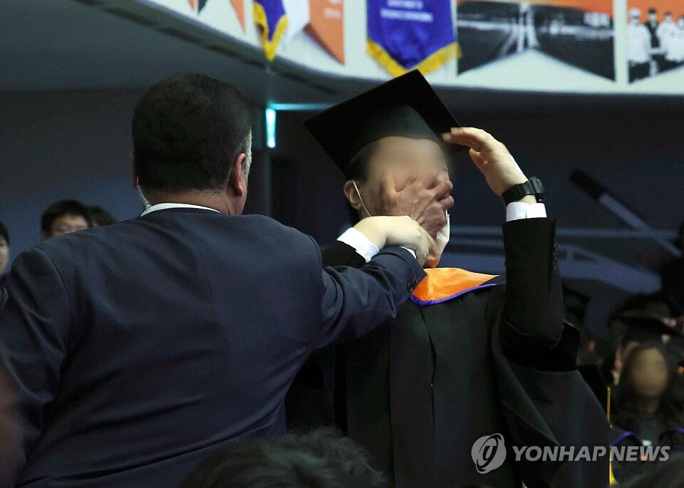 지난 2월 16일 대전 유성구 한국과학기술원(KAIST)에서 열린 2024년 학위수여식에서 한 졸업생이 윤석열 대통령이 축사를 할 때 R&D 예산과 관련해 자리에서 일어나 대통령을 향해 항의를 하던 중 제지를 당하고 있다 (대통령실사진기자단=연합뉴스)