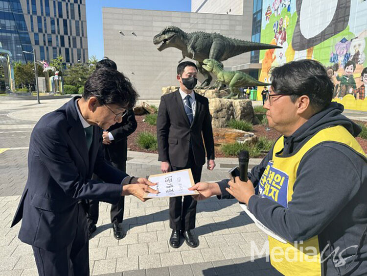 8일 박유준 언론노조 EBS지부장이 3차 출근을 시도하는 김성동 부사장에게 공개 질의서를 전달하고 있다. (사진=미디어스)