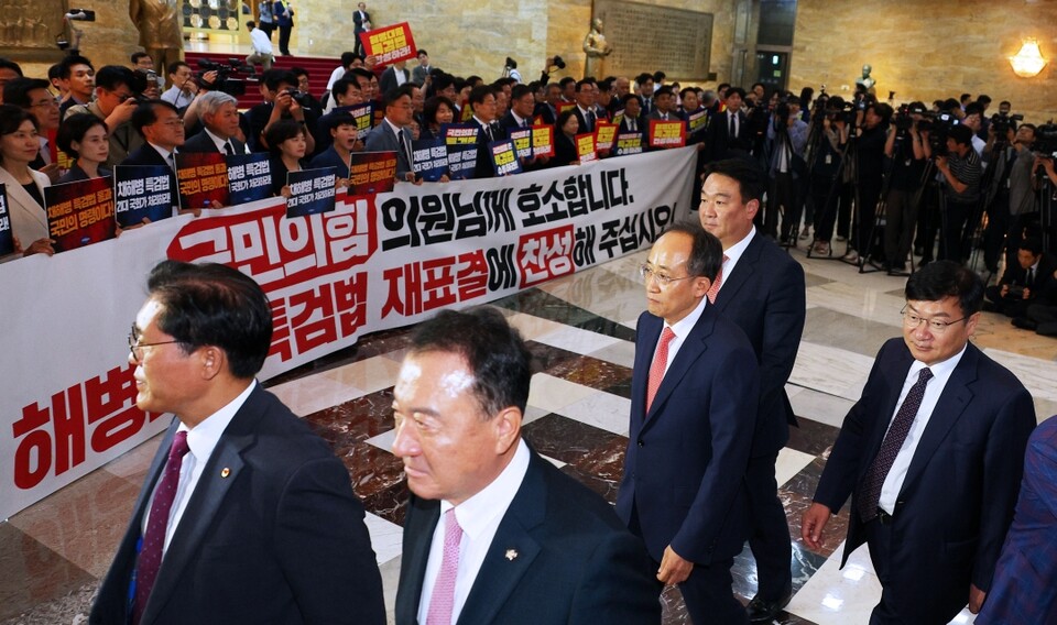 국민의힘 추경호 원내대표를 비롯한 의원들이 28일 오후 국회에서 열린 본회의에 참석하고 있다. 그 뒤로 야당 의원들이 해병대원 특검법 재표결 찬성을 촉구하고 있다 (사진=연합뉴스)