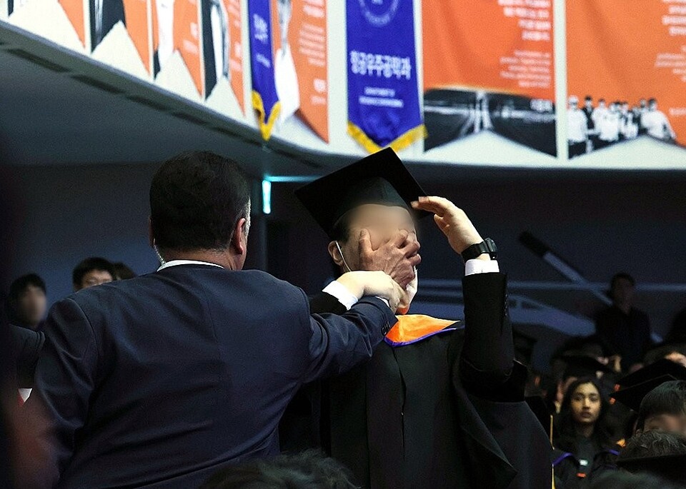 2월 16일 대전 유성구 한국과학기술원(KAIST)에서 열린 2024년 학위수여식에서 한 졸업생이 윤석열 대통령이 축사를 할 때 R&D 예산과 관련해 자리에서 일어나 대통령을 향해 항의를 하던 중 제지를 당하고 있다 (대통령실사진기자단=연합뉴스)