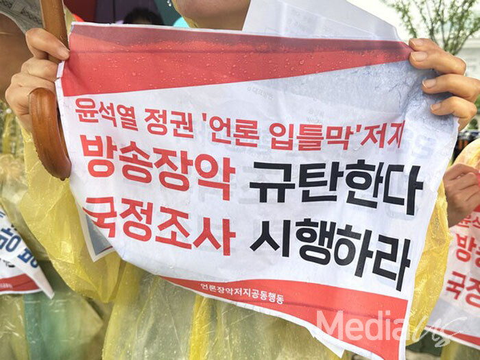 2일 국회 앞에서 열린 '방송4법' 의결 촉구 기자회견에서 한 참석자가 '방송장악 규탄' '국정조사 촉구' 팻말을 들고 있다.(사진=미디어스)