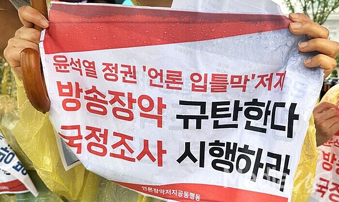 2일 국회 앞에서 열린 '방송4법' 의결 촉구 기자회견에서 한 참석자가 '방송장악 규탄' '국정조사 촉구' 팻말을 들고 있다.(사진=미디어스)