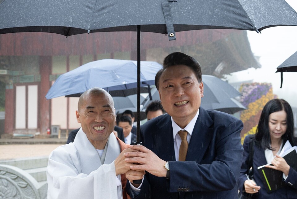 윤석열 대통령이 22일 부산 금정구 범어사를 찾아 대웅전 참배 뒤 주지 정오스님과 함께 우산을 쓰고 주지실로 이동하고 있다 (사진=대통령실 홈페이지)
