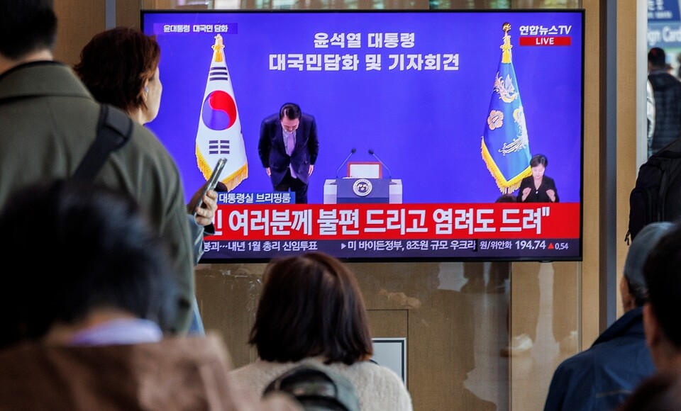 7일 시민들이 서울 중구 서울역에서 텔레비전 생중계되는 윤석열 대통령의 대국민 담화·회견 중 윤 대통령이 고개숙여 사과하는 모습을 지켜보고 있다 (사진=연합뉴스)