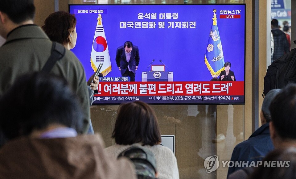 7일 시민들이 서울 중구 서울역에서 텔레비전 생중계되는 윤석열 대통령의 대국민 담화·회견 중 윤 대통령이 고개숙여 사과하는 모습을 지켜보고 있다. (서울=연합뉴스)