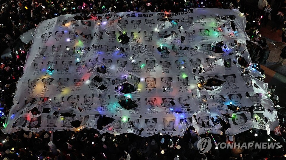 12일 오후 서울 영등포구 국민의힘 당 사무실 앞에서 열린 윤석열 대통령 탄핵 촉구 촛불 집회 행진에 참석한 시민들이 윤 대통령의 탄핵소추안 투표에 불참한 국민의힘 의원들을 규탄하는 현수막을 찢고 있다. (서울=연합뉴스)