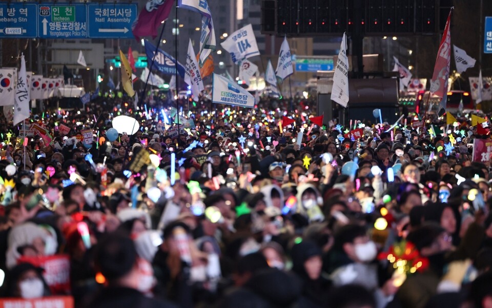 윤석열 대통령 탄핵소추안이 가결된 지난 14일 서울 여의도 국회 앞에서 열린 탄핵 촉구 집회에 참석한 시민들이 기뻐하며 노래를 따라 부르고 있다 (사진=연합뉴스)