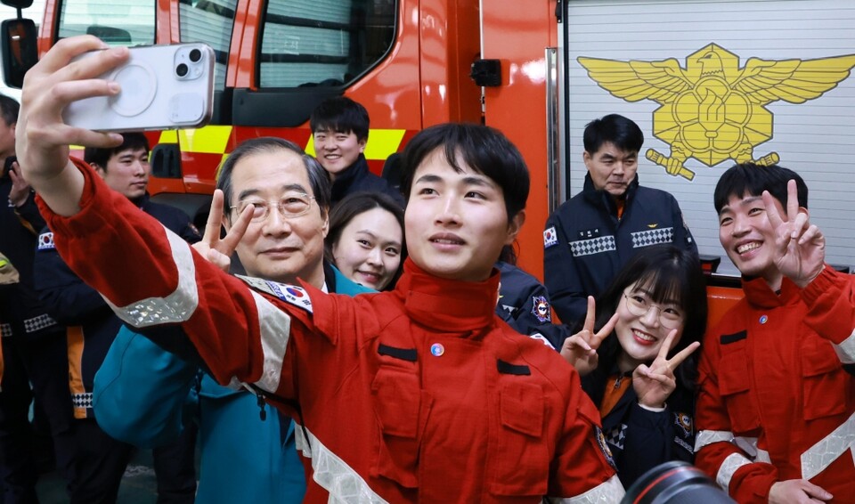 한덕수 대통령 권한대행(국무총리)이 지난 24일 서울 중부소방서를 방문해 연말연시 재난대응체계 등을 점검한 뒤 소방서 관계자들과 셀피를 찍고 있다. 한덕수 대행은 이날 내란·김건희 특검법 공포, 헌법재판관 임명 등을 여야 합의 없이는 할 수 없다는 입장을 밝혔다 (사진=연합뉴스)