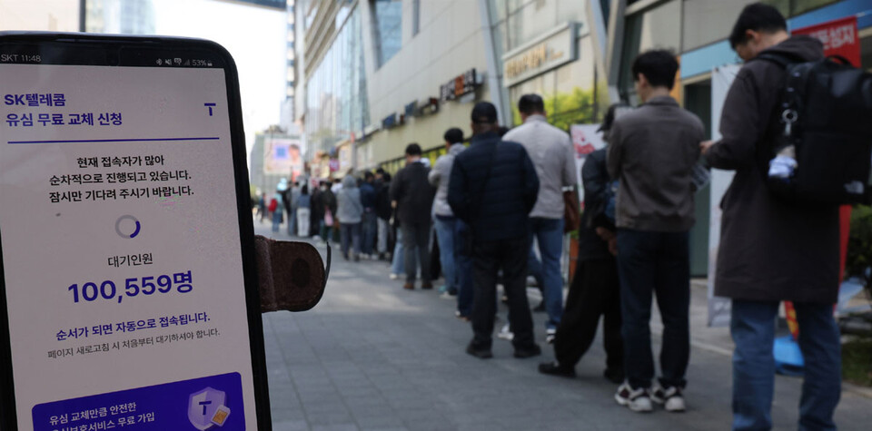 SK텔레콤이 유심 고객정보 해킹 사고로 관련 유심 무료 교체 서비스에 나선 28일 서울 시내 한 SK텔레콤 대리점 앞에서 한 고객이 유심 교체 예약을 QR코드로 등록하자 대기인원이 10만명 이상으로 나타나있다.(사진=연합뉴스)