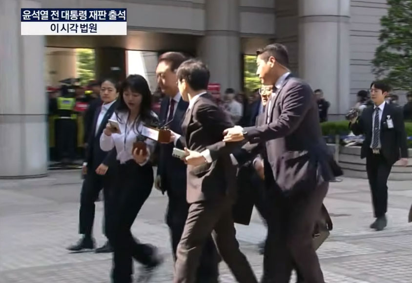 12일 경호처 직원이 윤 전 대통령에게 질문하는 기자의 팔을 붙잡고 제지하고 있다. (사진=KBS 유튜브 영상 갈무리)