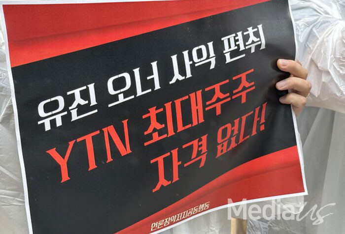 25일 여의도 유진빌딩 앞에서 열린 '공정위 신고' 관련 기자회견에서 참석자가 피켓을 들고 있다.(사진=미디어스)