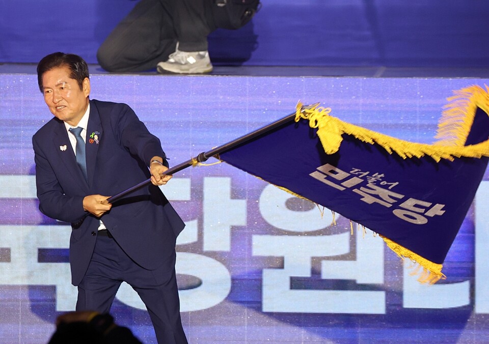 더불어민주당 정청래 신임 당대표가 지난 2일 고양 킨텍스에서 열린 전국당원대회에서 김병기 당대표 직무대행 겸 원내대표로부터 받은 당기를 흔들고 있다 (사진=연합뉴스)