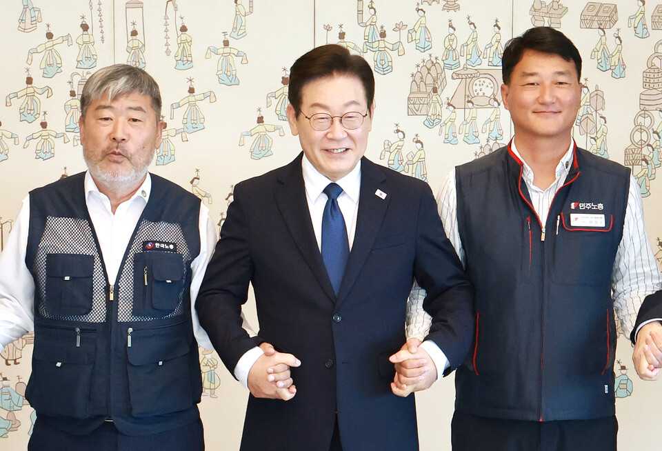 이재명 대통령이 4일 서울 용산 대통령실 청사에서 열린 양대노총 위원장과의 오찬 간담회에 참석해 김동명 한국노총 위원장(왼쪽), 양경수 민주노총 위원장과 기념촬영을 하며 손을 잡고 있다. (연합뉴스)