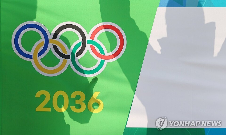 대한체육회 대의원총회를 통해 2036 하계 올림픽에 도전할 국내 유치 도시가 결정되는 2월 28일 총회를 앞둔 서울 송파구 올림픽파크텔 앞에서 응원전을 펼치는 한 관계자의 모습이 오륜마크와 2036 숫자 위로 비치고 있다. (서울=연합뉴스)