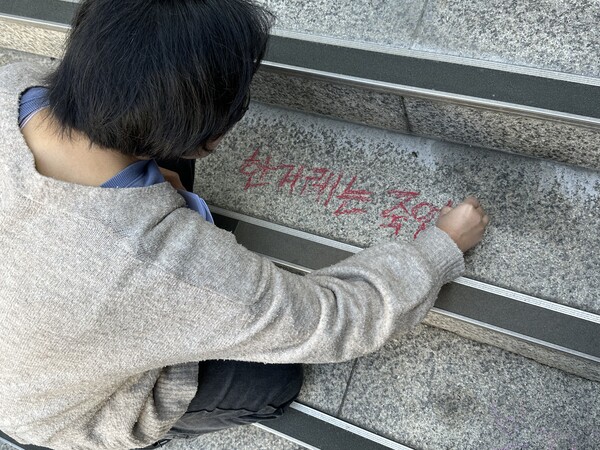 한 참석자가 한겨레 사옥 앞 계단에 붉은 글씨로 '한겨레는 죽었다'라고 적고 있다.(사진=미디어스)